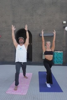 Two people with arms raised overhead during a Ren Zen yoga class on the pool deck at the Renaissance Reno Downtown Hotel